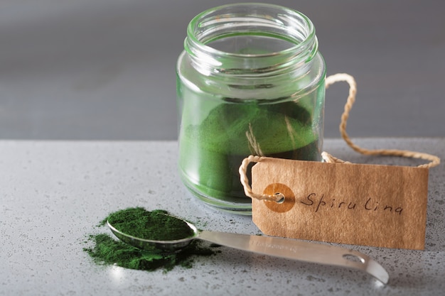 Spirulina-Pulver in einem Löffel und Glas