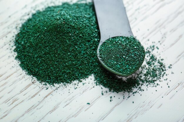 Foto spirulina-pulver und messlöffel auf hölzernem hintergrund