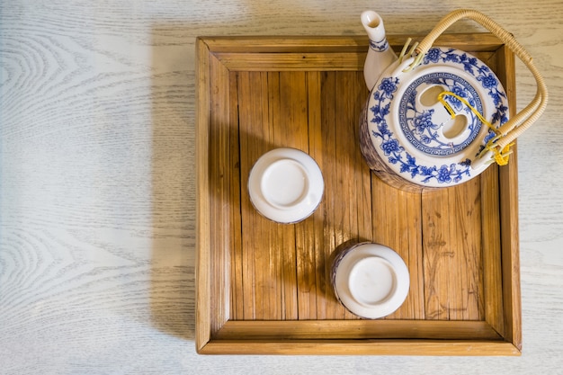 Spitze der traditionellen weißen Tasse Tee und der Teekanne in der hölzernen Behälternahaufnahme auf Tabelle