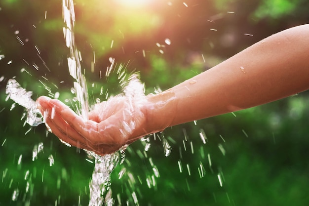 Foto splash de colada de agua en la mano y el fondo de la naturaleza