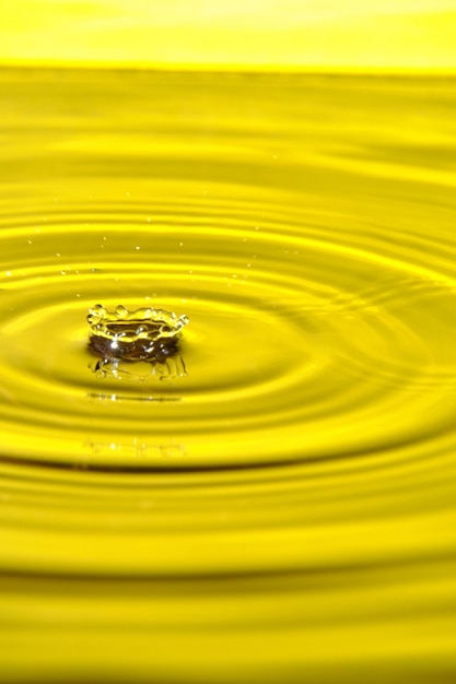 Splash gota de água com círculos de água divergentes em fundo amarelo