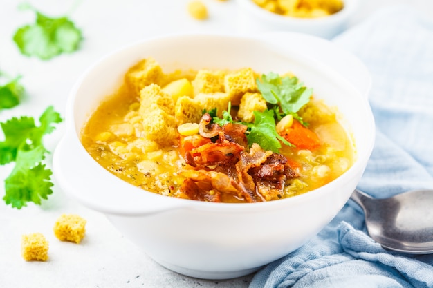 Split sopa de guisantes con tocino ahumado y galletas en un plato blanco.