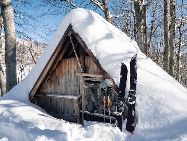 Splitboard und Stöcke im Schnee im Holzhaus der Hirten vergießen Hintergrund Sportausrüstung für Skitouren