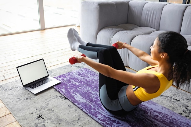 Foto sport afroamerikanische frau, die online sport mit laptop-computer macht. fitness zu hause. technologiekonzept