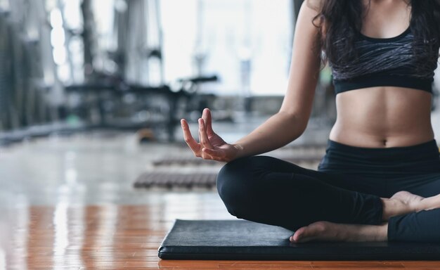 Sport asiatische frau praktizieren yoga-lektion atmen meditierend dabei ardha padmasana übung trainieren im fitnessstudio