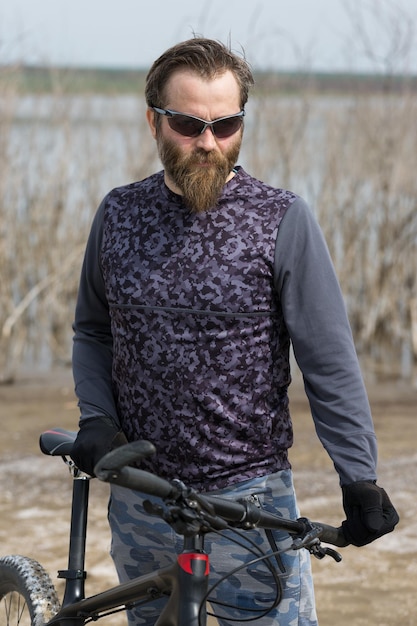 Sport brutaler bärtiger Kerl auf einem modernen Mountainbike Ein Radfahrer an einem salzwüsten Ort am See