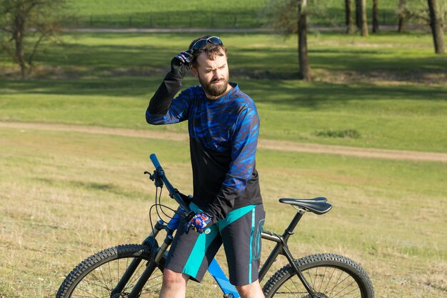 Sport brutaler bärtiger Kerl auf einem modernen Mountainbike. Schöne Aussicht vom Berg.