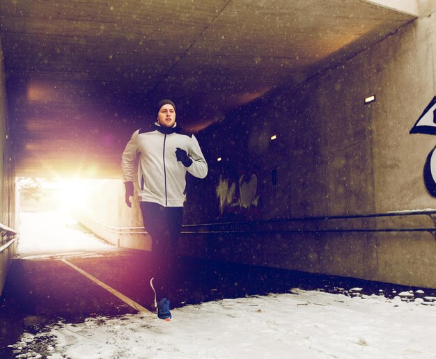 Foto sport-fitness-leute saison und gesunder lebensstil konzept junger mann läuft entlang fußgänger u-bahn-tunnel im winter