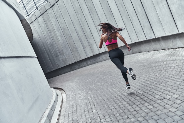 Sport ist ihr Lebensweg. Rückansicht in voller Länge der jungen Frau in Sportkleidung beim Joggen im Freien