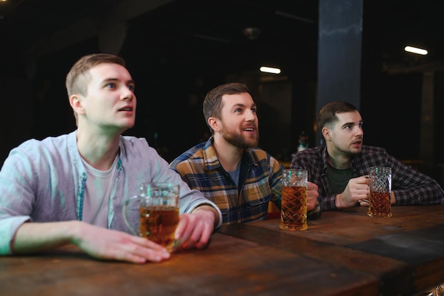 Sport Menschen Freizeit Freundschaft Unterhaltungskonzept glückliche männliche Fußballfans oder gute junge Freunde, die Bier trinken und den Sieg in der Bar oder im Pub feiern Menschliche positive Emotionen Konzept