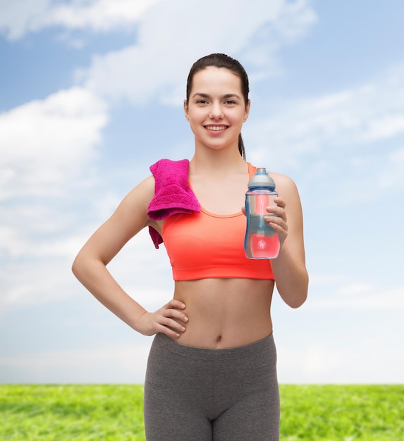 sport, übung und gesundheitswesen - sportliche frau mit rosa handtuch und wasserflasche