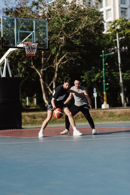 Sport- und Erholungskonzept zwei männliche Basketballspieler, die gemeinsam Basketball auf dem Sportplatz spielen.
