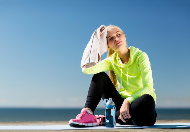 Sport- und Lifestyle-Konzept - Frau, die sich nach dem Sport im Freien ausruht