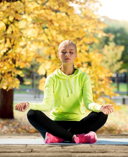 Sport- und Lifestyle-Konzept - Frau macht Yoga im Freien