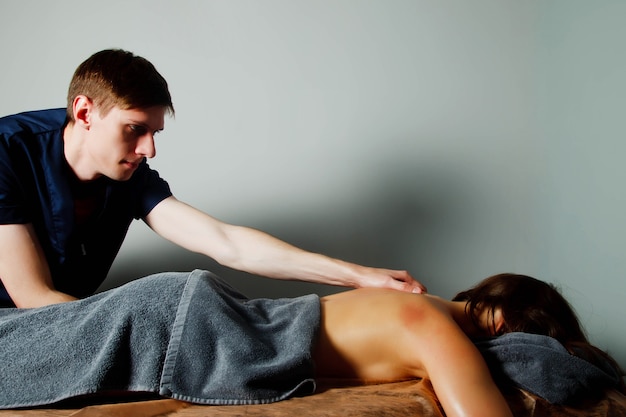Sport Wellness-Massage im medizinischen Raum des Fitness-Studios. Masseur macht Massageübungen. Therapeutische regenerierende Massage des Sportkörpers. Konzepte der Rehabilitation von Sportverletzungen. Platz kopieren