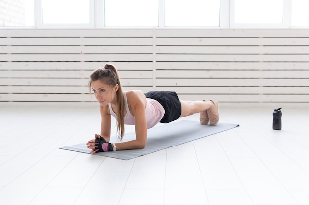 Sport, Yoga, Menschenkonzept - eine junge Frau macht eine Planke, Yoga, balanciert.