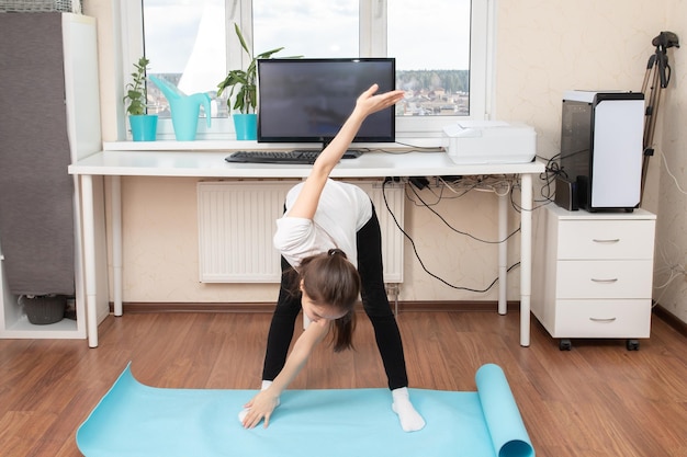 Sport zu Hause treiben Junge Frau, die Übungen macht und auf den Monitor schaut