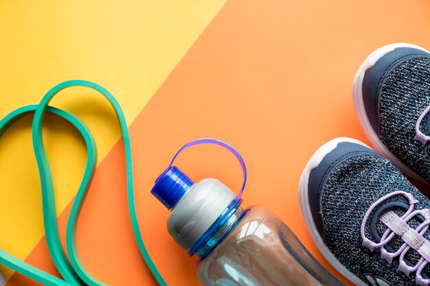 Foto sportausrüstung, blaue turnschuhe, springseil und eine flasche wasser. gesunder lebensstil, fitnesskonzept.