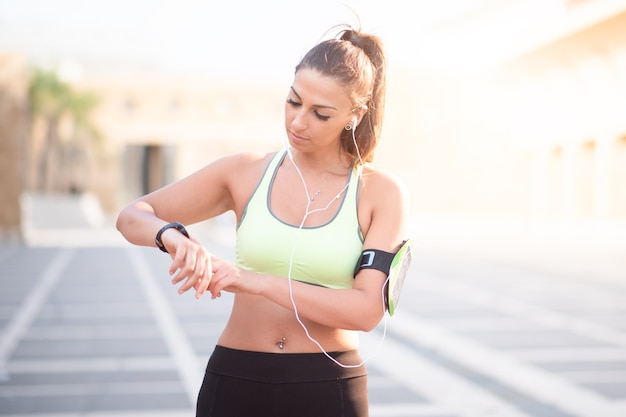 Sportdame im Freien Musik hören mit Kopfhörern mit Handy