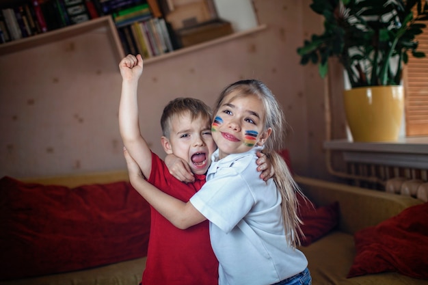 Sportfan mit farbigen Wangen, die auf dem Sofa sitzen, Sportspiele beobachten und das Team online zu Hause anfeuern, echte Emotionen, Sportereignisse und sichere Spaßunterstützung, sozial entferntes Jubeln während des Lockdowns