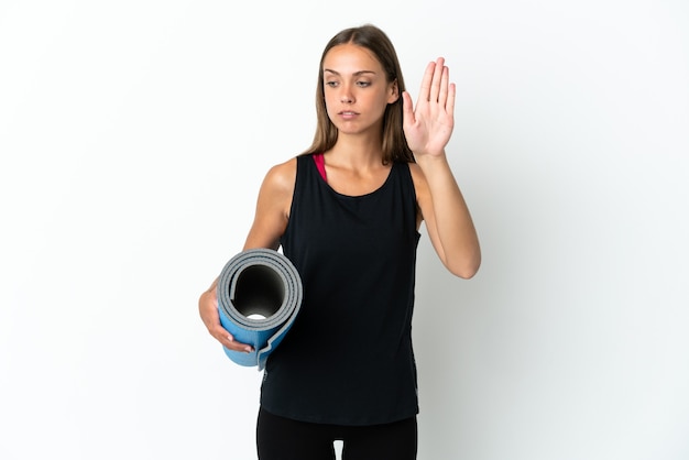 Sportfrau, die zu Yoga-Kursen geht, während sie eine Matte isoliert hält