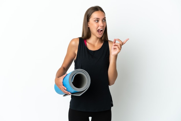Sportfrau, die zu Yoga-Kursen geht, während sie eine Matte über isoliertem weißem Hintergrund hält, um die Lösung zu realisieren, während sie einen Finger anhebt