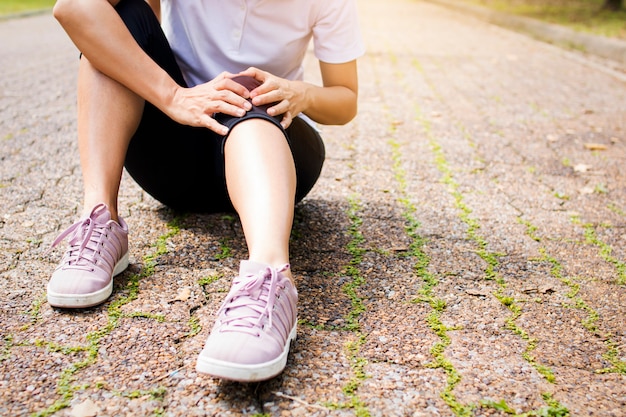 Sportfrau hat Knieschmerzen oder Beinverletzung nach dem Training im Park