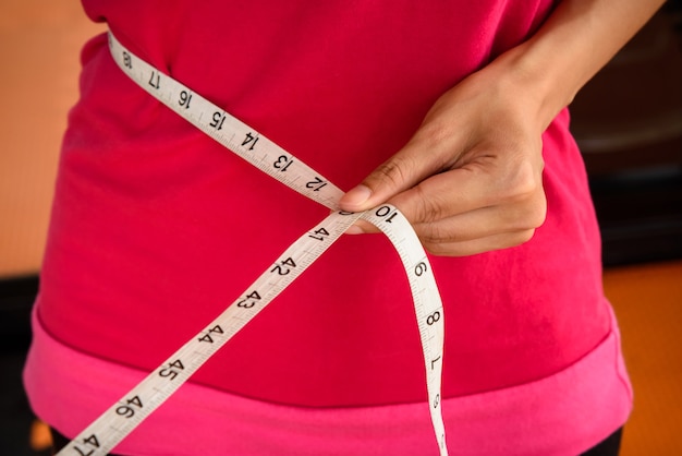 Sportfrau mit messendem Band auf einer schlanken ihre Taille