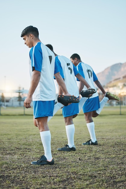 Sportgruppenfußball und Team strecken auf dem Spielfeld die Beine für Fitnesstraining oder Muskelaufwärmen. Fußballspielerverein und Diversity-Athleten mit Fokus auf sportliches Wettkampftraining oder Herausforderung