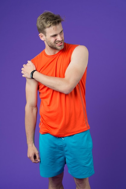 Sportler berühren Schulter auf violettem Hintergrund Muskulöser Mann empfindet Schmerzen nach dem Training oder Training Schmerzen in der Schulter Sportverletzung Ich brauche eine Massage Gesundheitsversorgung und Behandlung Körperpflege und Wellness