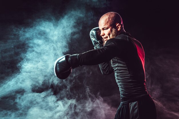 Sportler-Boxer, der auf Schwarzraum mit Rauch kämpft