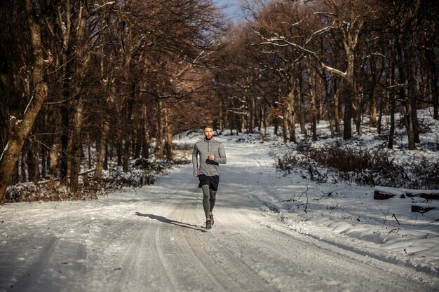 Sportler, der in der Natur auf Schnee im Winter läuft