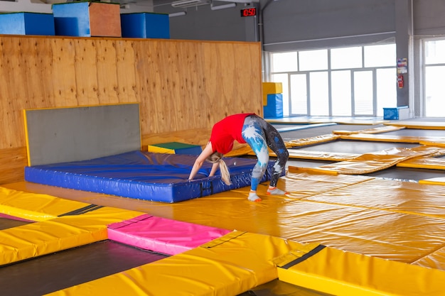 Sportler der jungen Frau auf einem Trampolin im Fitnesspark und beim Training im Haus.