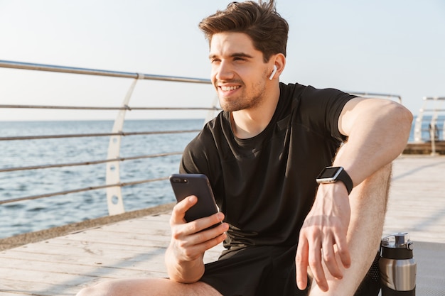 Sportler draußen am Strand Musik hören