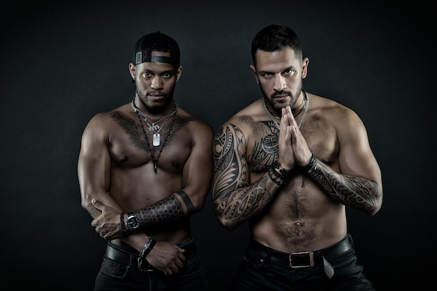 Sportler mit sexy fitten Oberkörpern Kampfsportler beruhigen sich vor dem Kampf Bodybuilder isoliert auf schwarzem Hintergrund Hispanischer Mann mit geometrischen Tätowierungen, die Hände in Gebetsgeste halten