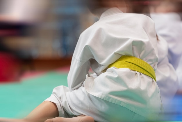 Sportler-Teenager im weißen Kimono mit gelbem Gürtel auf der Tatami vor dem Kampf Das Konzept der visuellen Bewegungsunschärfe und der geringen Schärfentiefe