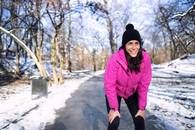 Sportlerin, die im Park während des Schnees und des Winters läuft.