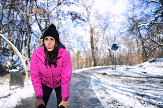 Sportlerin, die im Winter während des Schnees im Park trainiert.