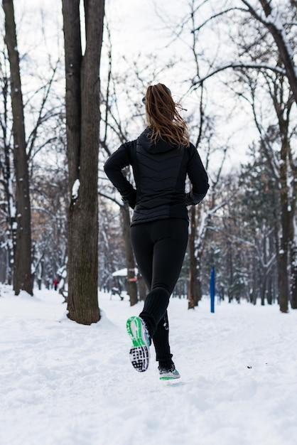 Sportlerin joggt an einem Wintertag im Park im Park