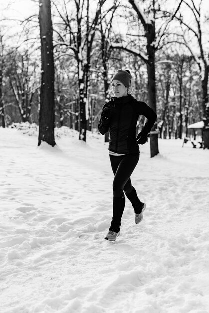 Sportlerin joggt an einem Wintertag im Park im Park