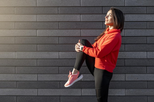 Sportlerin, Läuferin, die sich im Freien auf einem Jogger an der frischen Luft ausruht, macht eine Pause und trägt ein Sportoutfit