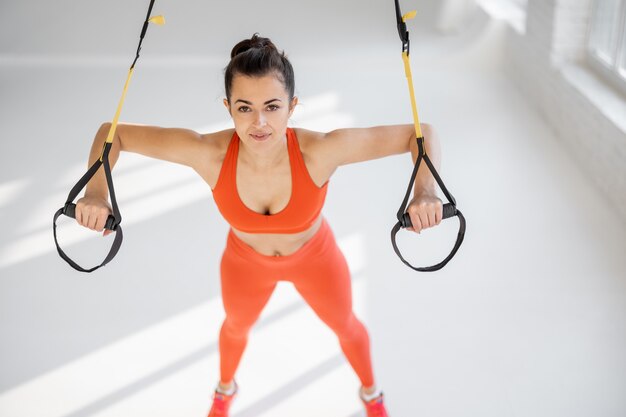 Sportlerin macht Liegestütze an TRX-Trägern