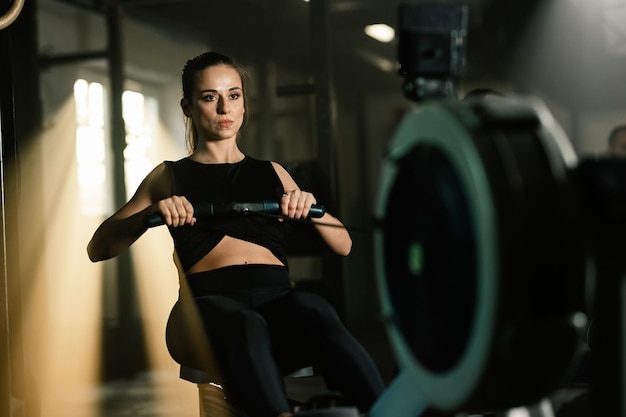 Sportlerin mit Cross-Training auf Rudergerät im Fitnessstudio