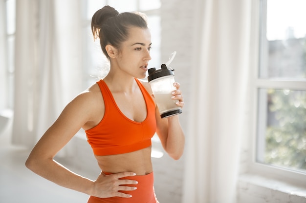 Sportlerin mit Protein-Shaker im Fitnessstudio