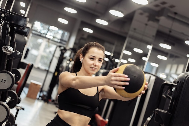 Sportlerin trainiert mit Medizinball in den Händen im Fitnessstudio