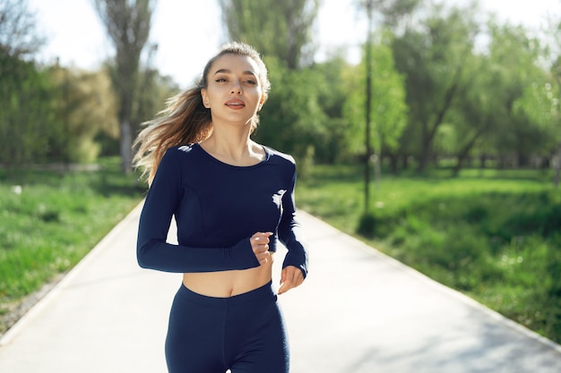 Sportlich fitte junge Frau, die früh morgens im Park joggt