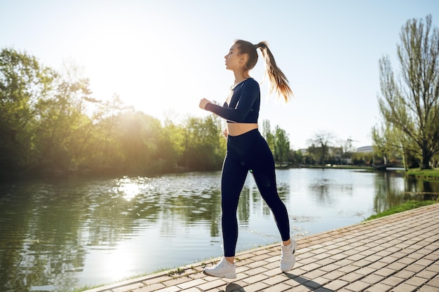 Sportlich fitte junge Frau, die früh morgens im Park joggt