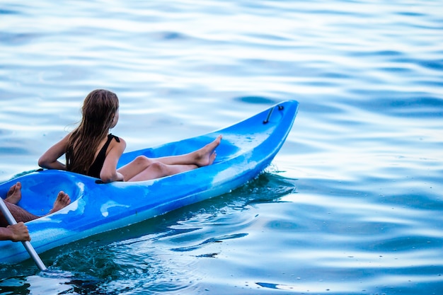 Sportliche attraktive Familie, die zusammen auf Meer Kayak fährt