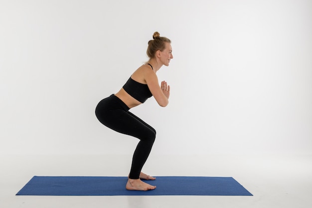 Sportliche attraktive junge Frau, die Yoga-Praxis auf weißem Hintergrund tut. Kursiasana.