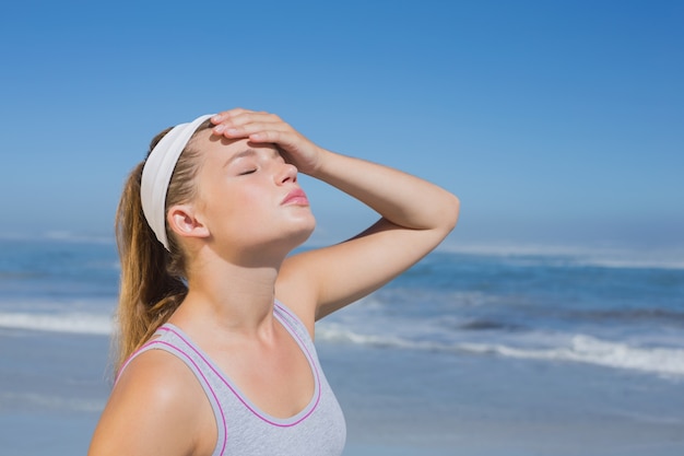 Sportliche Blondine, die auf dem Strand steht